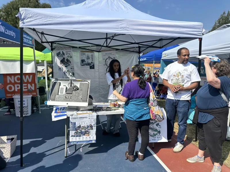 Staff member handing outreach materials to a community member at an electronics reuse event