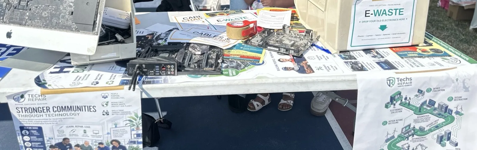 Electronics reuse display with disassembled iMac, circuit boards, and an e-waste collection bin