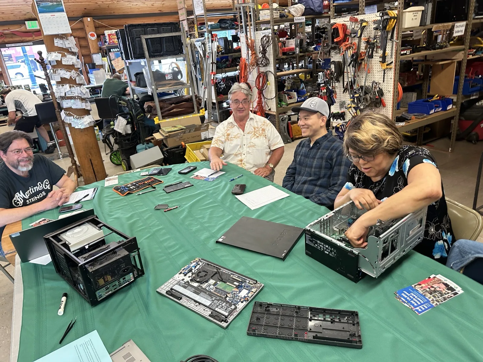 Hands-on electronics repair workshop with participants working on disassembled desktop computers