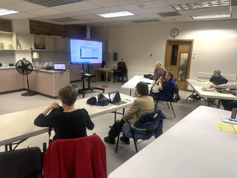 Group technology training session with attendees watching a software demonstration on a large screen